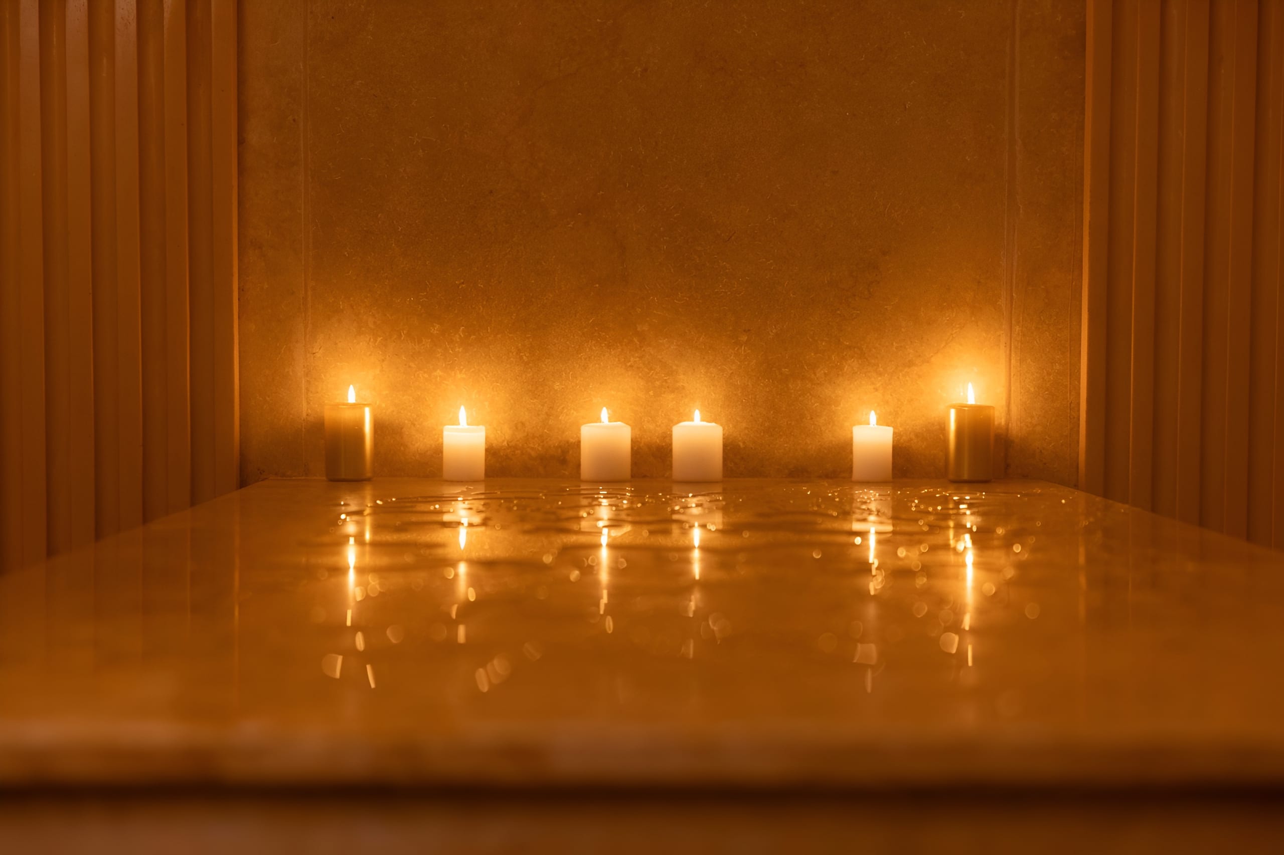 Banco de mármol del hammam con una hilera de velas