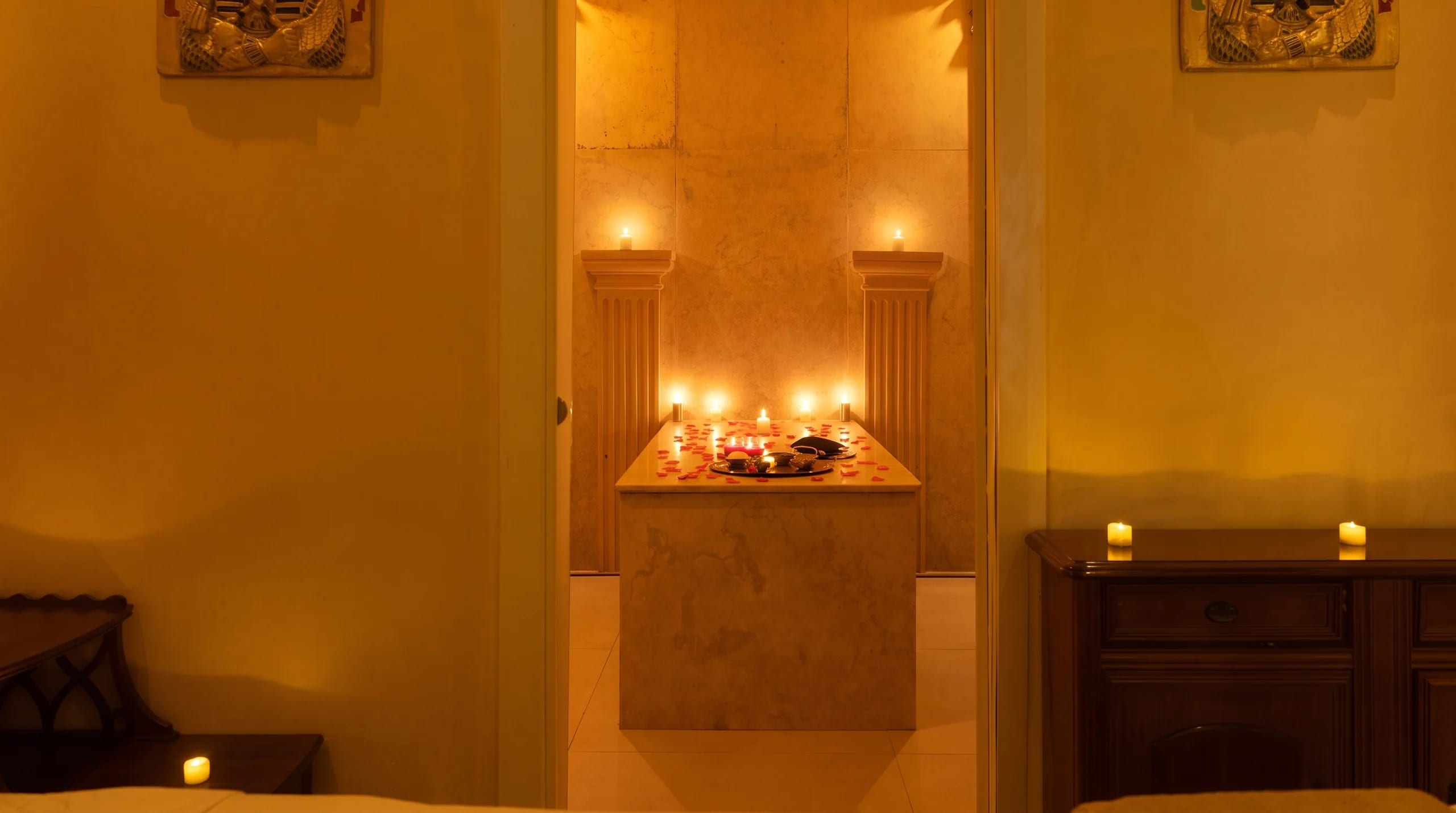 Cabina en penumbra con la puerta abierta al hammam iluminado con velas